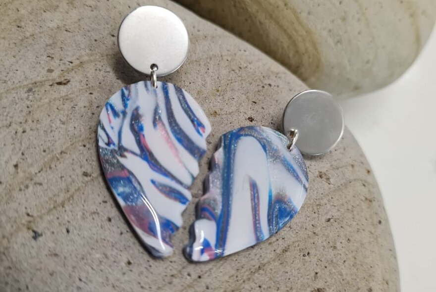 A pair of polymer clay earrings shaped as two halves of a love heart shape.