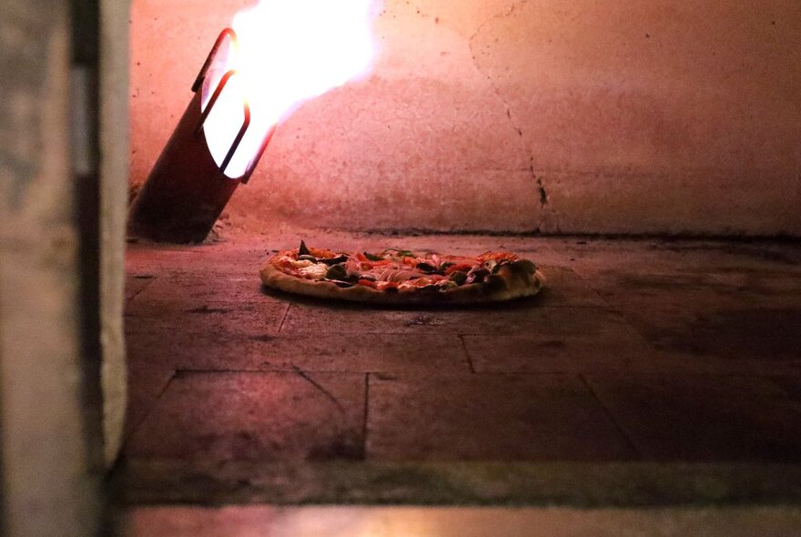 Interior of a pizza oven with a pizza baking in it.