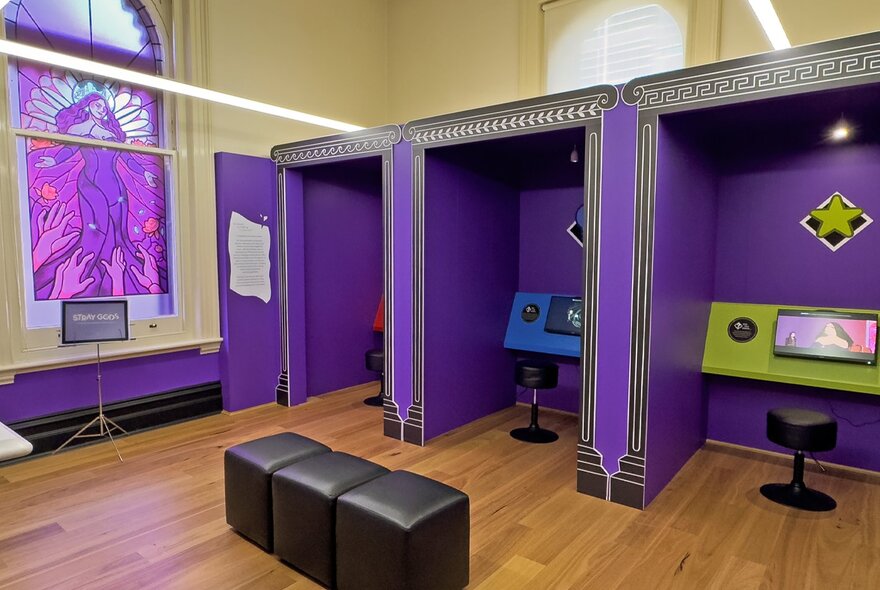 A room with three purple gaming booths. 