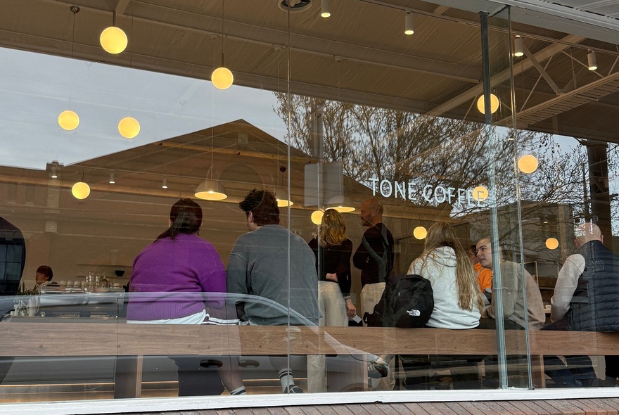 Exterior of Tone Coffee Roasters with patrons inside the cafe eating and drinking.