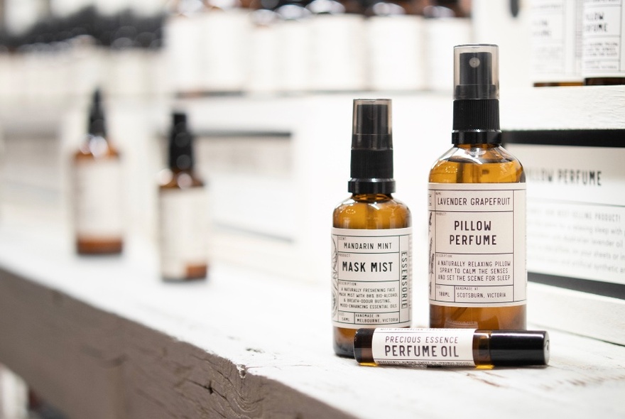 Small amber bottles with white and black labels on a shelf, containing mist and perfumes.