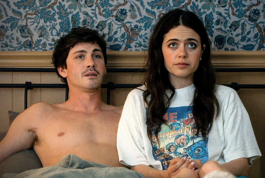 A still from the film, Oh, Hi! showing a young couple sitting up next to each other in bed.