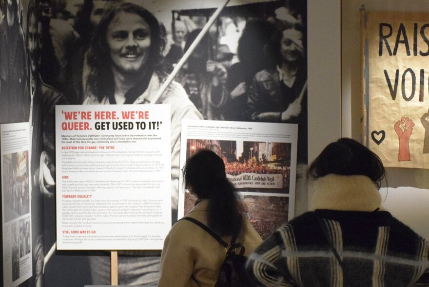 Person in a room looking at a exhibition material displayed on a wall.