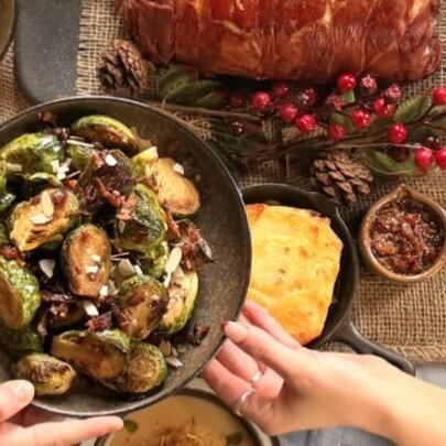 Christmas roast dinner feast of pork and brussels sprouts with hands reaching for plate.