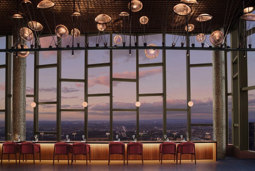 Looking out of ladder shaped windows at dusk from a hotel dining room. 