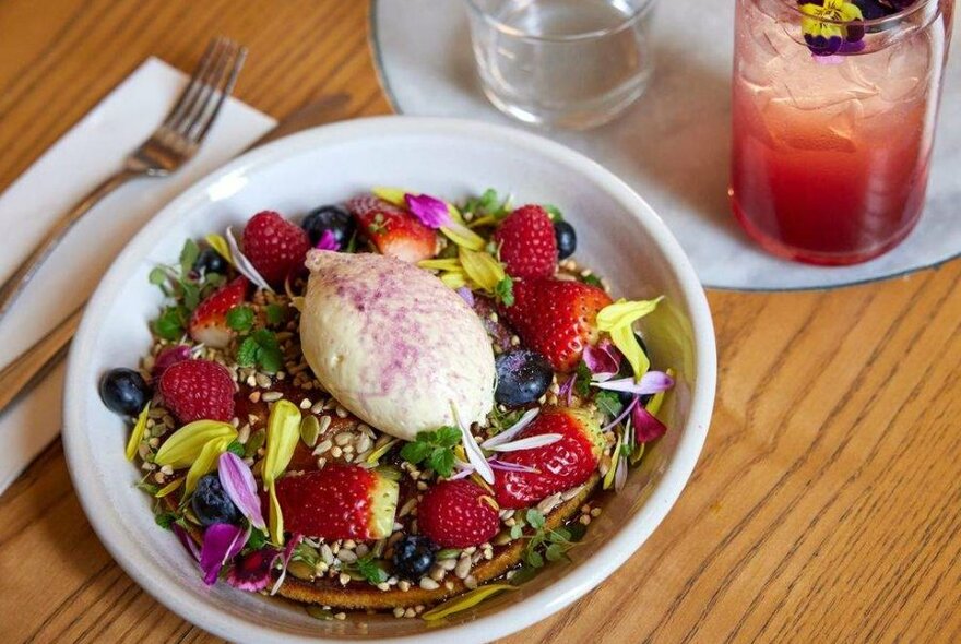 A pancake on a plate covered in fruit and flowers