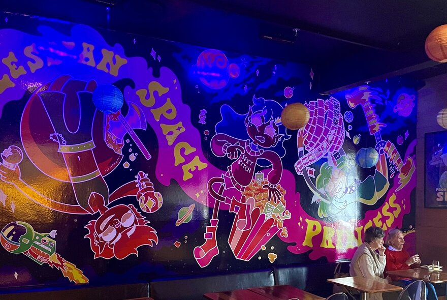 Mural with swirling writing on the wall of a bar.