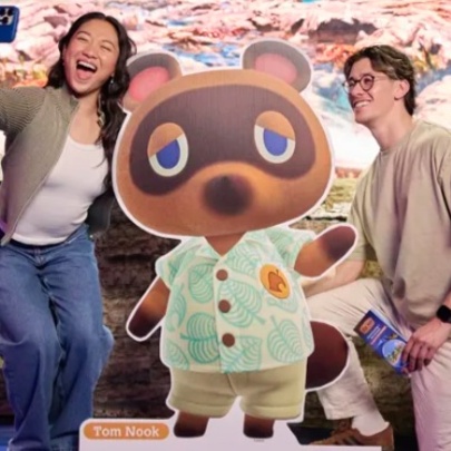People taking a selfie with an animation character.