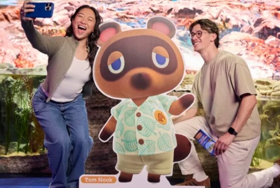 People taking a selfie with an animation character.