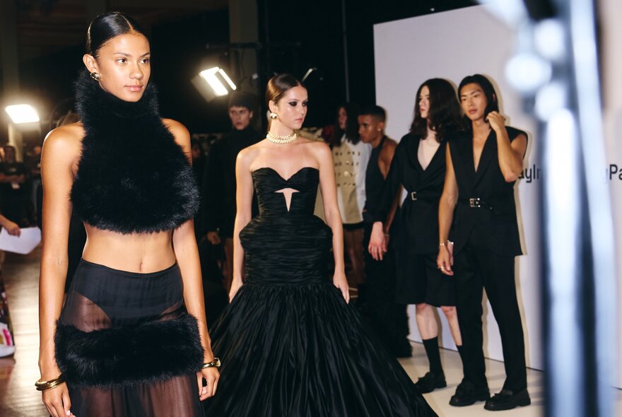 Models backstage and on the runway at a fashion festival, featuring dramatic black-and-gothic styling.