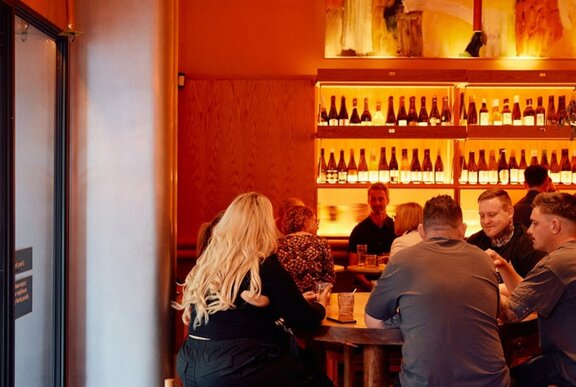 A group of people at a table in front of a bar.