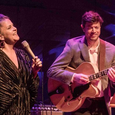 Jazz vocalist Michelle Nicolle performing live on a stage alongside jazz guitarist Hugh Stuckey.
