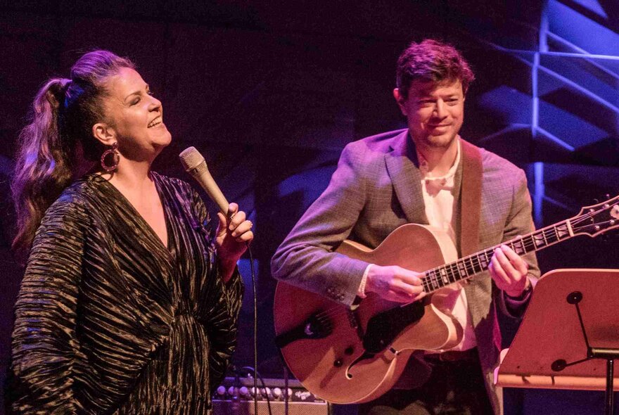 Jazz vocalist Michelle Nicolle performing live on a stage alongside jazz guitarist Hugh Stuckey.