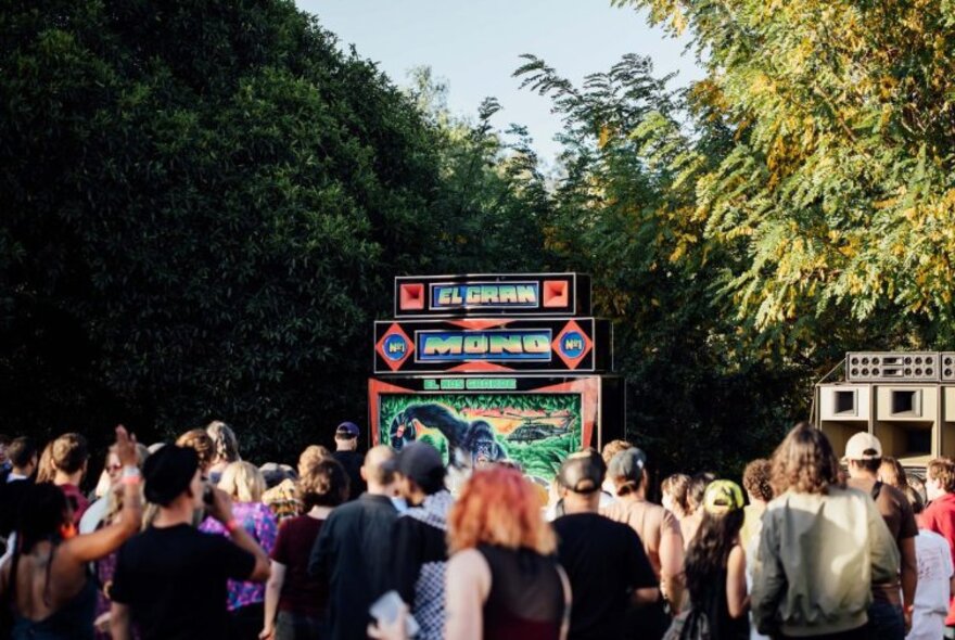 People outdoors in a public garden setting listening to music coming out of coloured speakers.