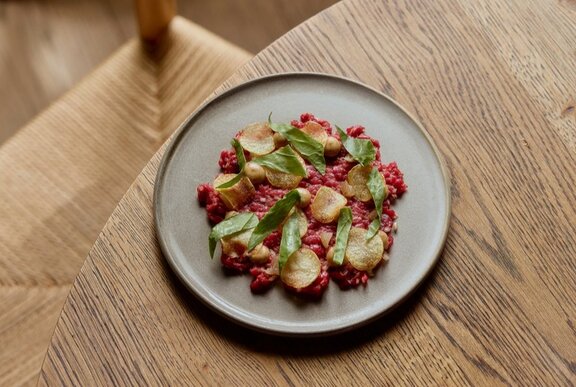 Steak tartare dish with garnish on a wooden table.