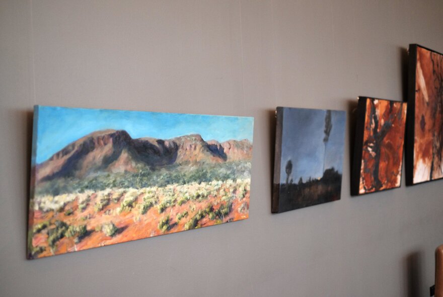 Artworks of Australian landscapes hanging on a grey wall.