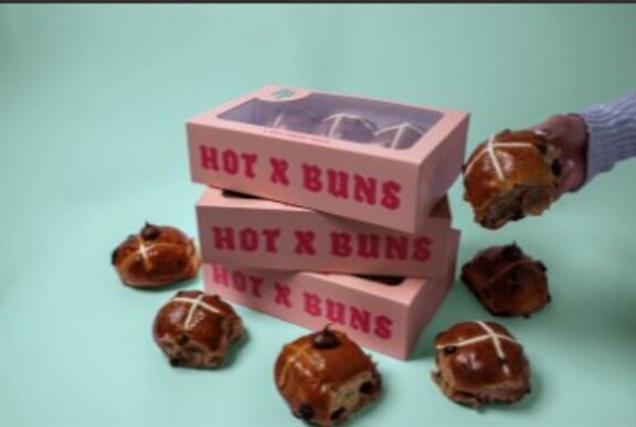 Box of branded hot cross buns, surrounded by buns.