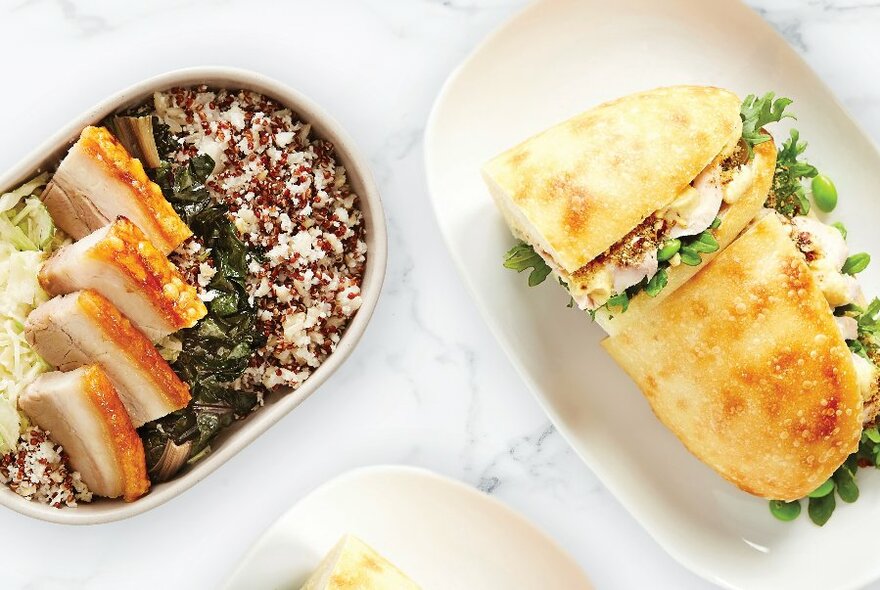 A table with a pork and rice bowl and a chicken and rocket focaccia