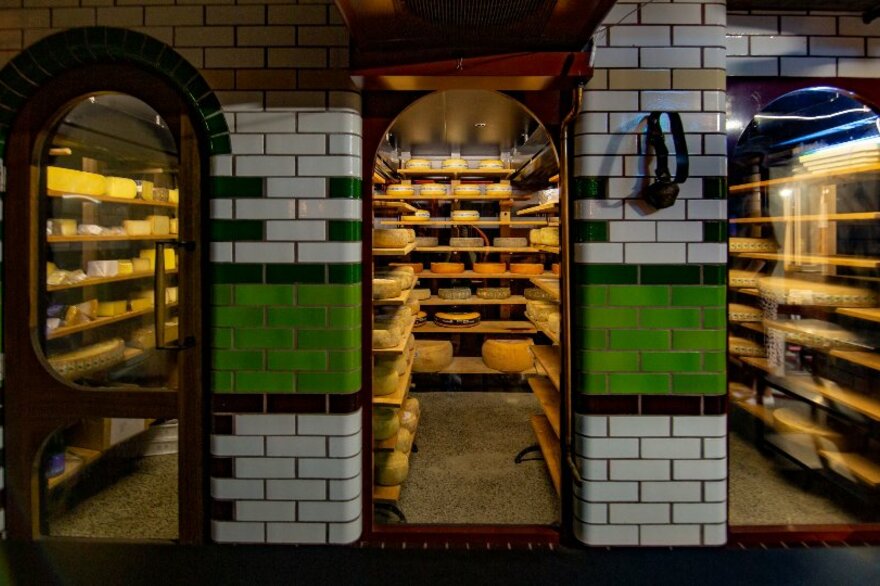 Arched windows looking into an underground cellar full of cheese