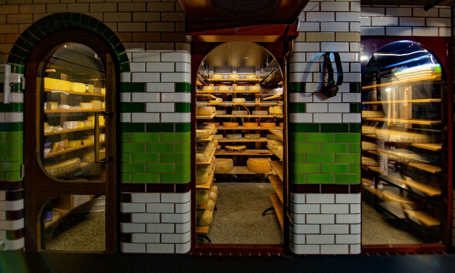 Arched windows looking into an underground cellar full of cheese