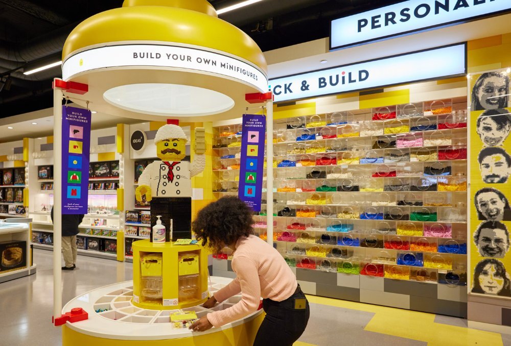 A person using the build-your-own Lego person wall inside a shop.