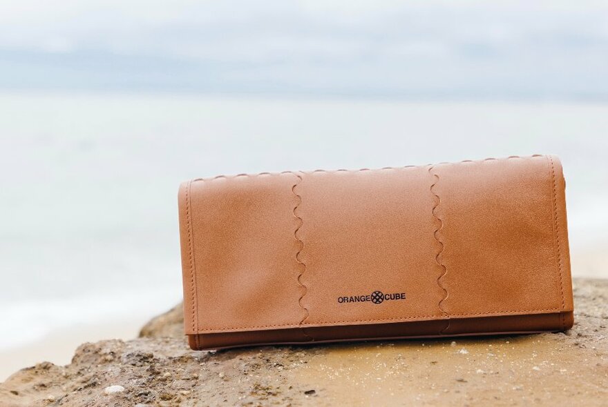 Tan clutch resting on sand.