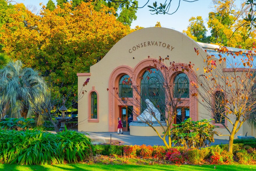 A child walking into a conservatory building in a garden.