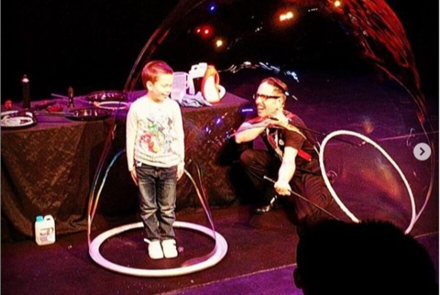 Performer placing a bubble over a small child.