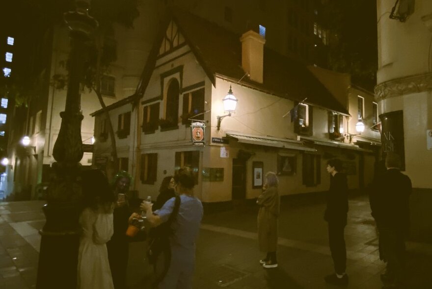 People outside an old building in a dark laneway at night.