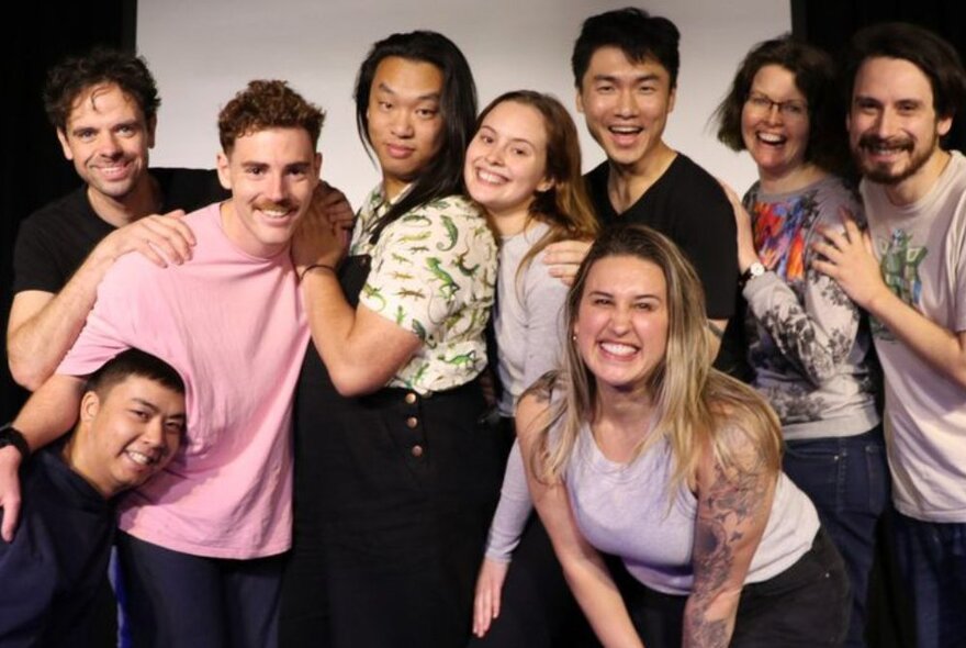 Group of people laughing and posing against a white projector screen.