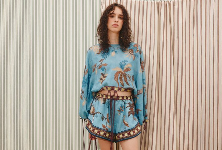 A model wearing a matching blue crop top and shorts with a burgundy leaf print.