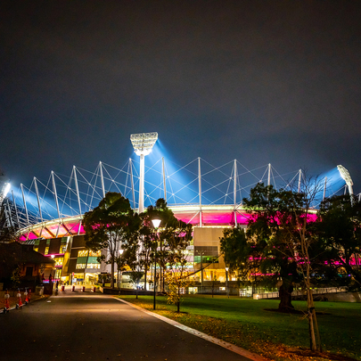 MCG football stadium lit up pink at night.
