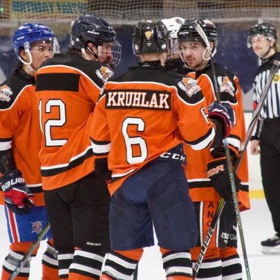Players from the Melbourne Mustangs ice hockey team wearing their orange and black jerseys during an ice hockey league match on an ice rink.