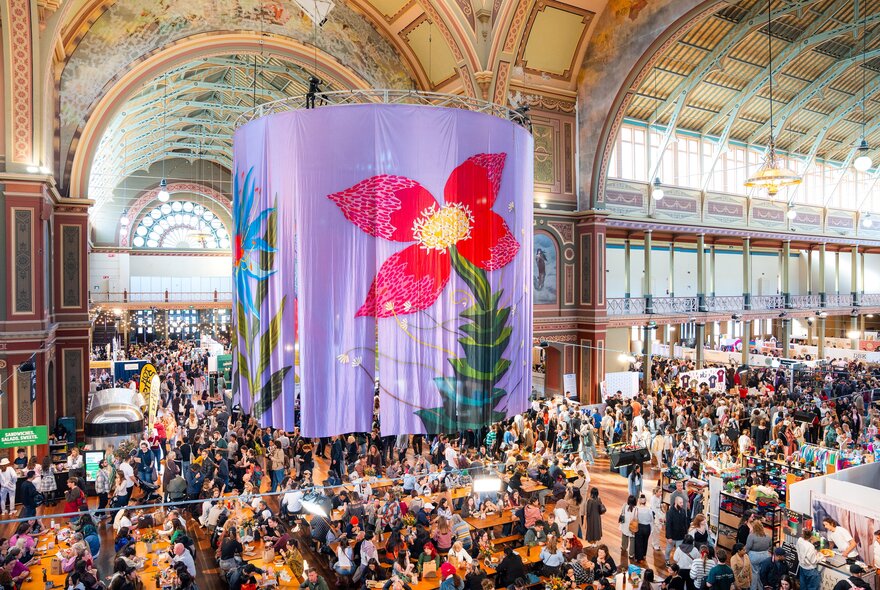 Market stalls in Royal Exhibition Building with floral flag display.