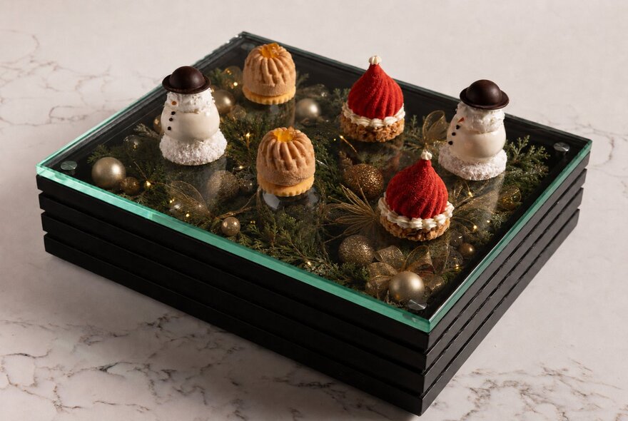 Christmas pâtisserie, including snowman pavlova and Santa’s hat cheesecake, presented in a black box.