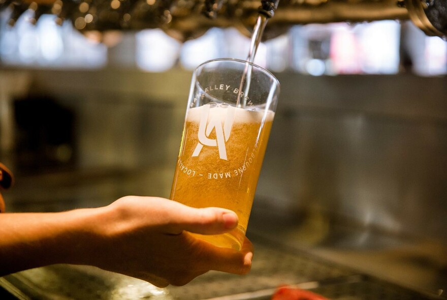 A glass of beer being poured from a tap. 