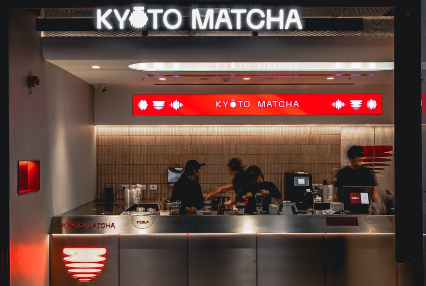 The counter of Kyoto Matcha with the name in neon over a workspace where staff are preparing drinks. 