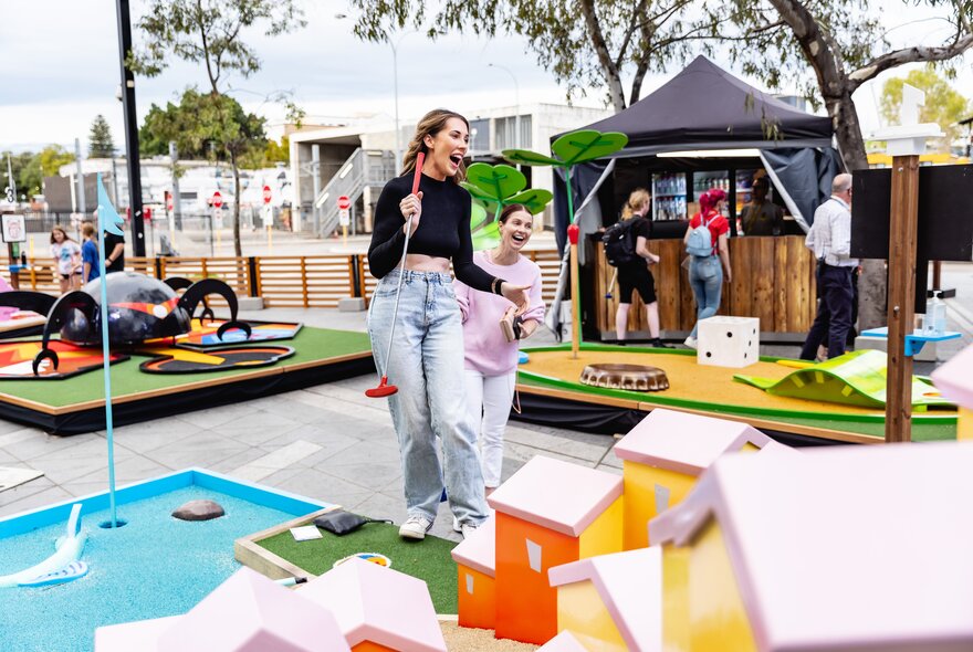 Children playing minigolf in an outdoor setting.