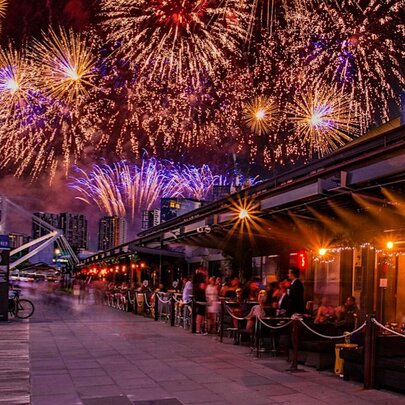 Fireworks over a restaurant with outdoor seating.