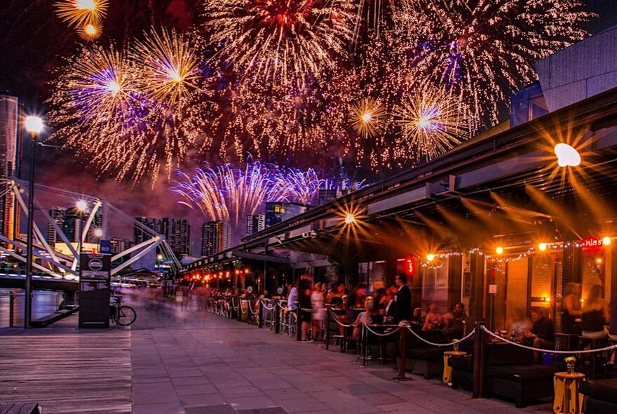 Fireworks over a restaurant with outdoor seating.