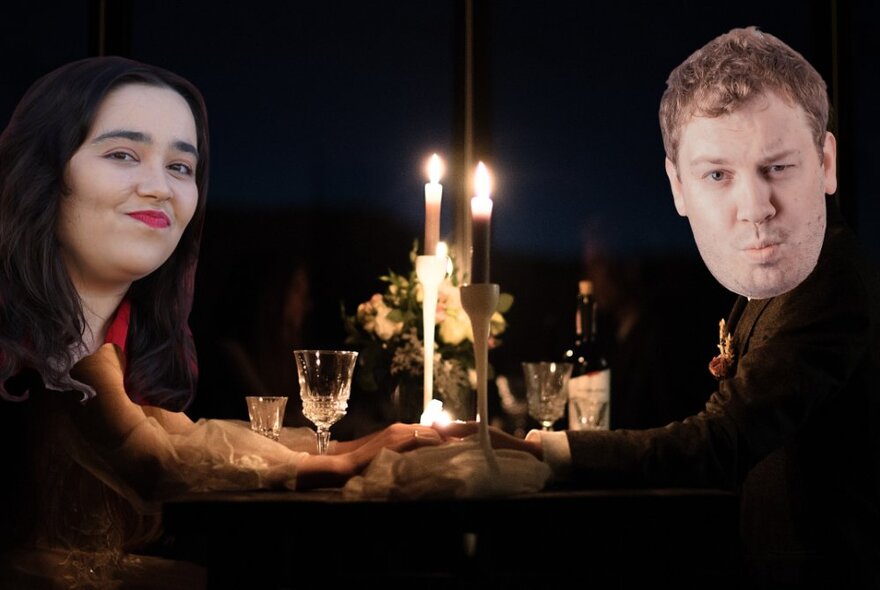 Two oversized cut-out faces of the performers in this show, superimposed onto the bodies of two people sitting opposite each other holding hands, at a candlelit table at a restaurant, as if on a date.