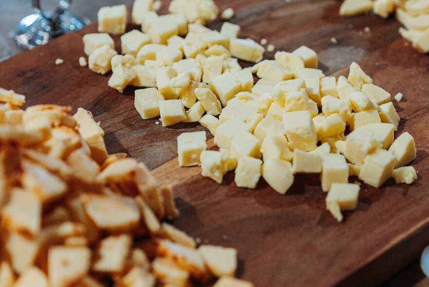 A wooden tray with small cubes of cheese on it.