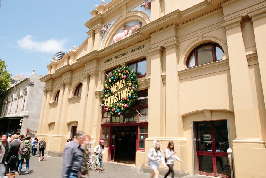 The front entrance of the Queen Victoria Market with a large Christmas wreath at the front. 