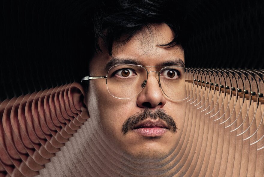 Face of comedian Phil Wang, he wear rimless glasses and has a mustache and a visual effect makes his neck and shoulders appear as many stacked layers.