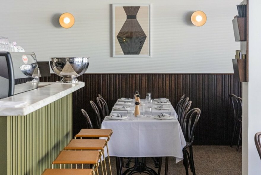 Looking at an elegant restaurant setting before the diners arrive with a set table and green bar. 