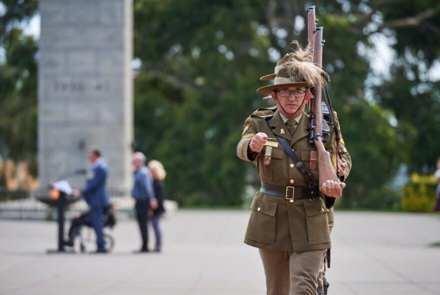 Row of soldiers marching towards camera in Shrine of Remembrance forecourt.