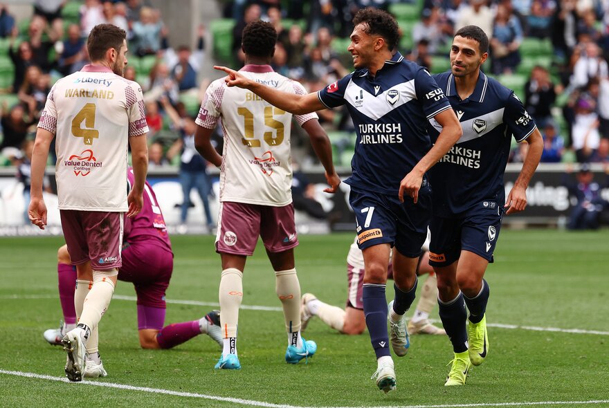 Soccer players on a field running and pointing. 
