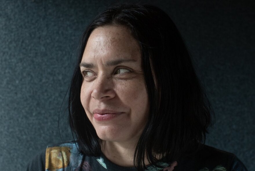 Colour portrait of writer Mandy Ord, with a slight smile and her head turned to one side.