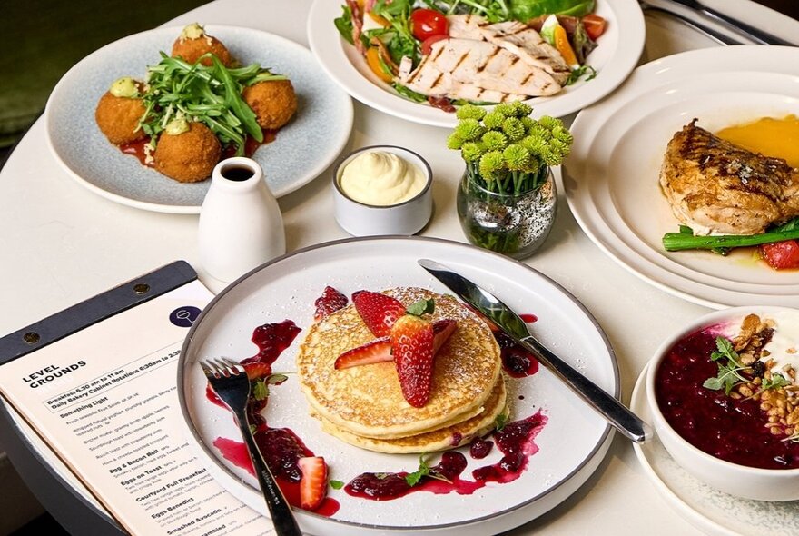 A brunch spread with the table filled with a variety of breakfast and lunch options, including fresh fruit, pancakes, and savoury dishes. 