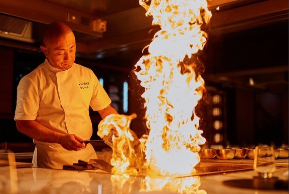 Chef using fire as a cooking technique in a restaurant kitchen.